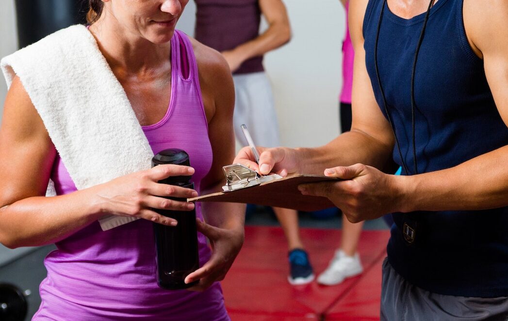 Male and female athletes discussing over clipboard